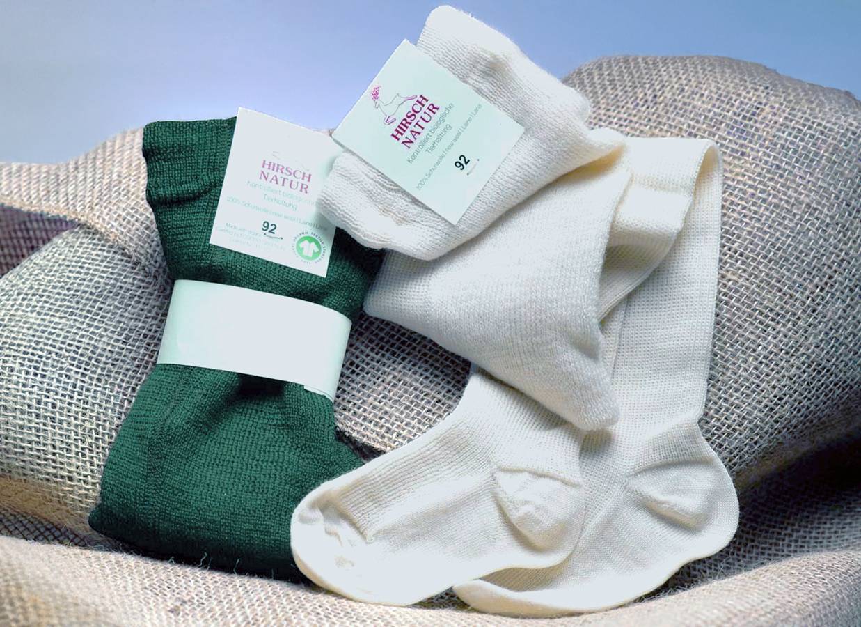 Zwei Paare Hirsch Natur Strumpfhosen auf einem Jutesack: eine dunkelgrüne und eine cremefarbene